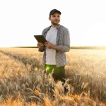 Landwirt untersucht das Getreidefeld und sendet Daten vom Tablet in die Cloud. Smart Farming und digitale Landwirtschaft.