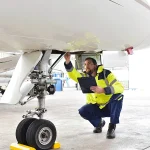 Mechaniker kontrolliert Fahrwerk eines Flugzeuges im Hangar