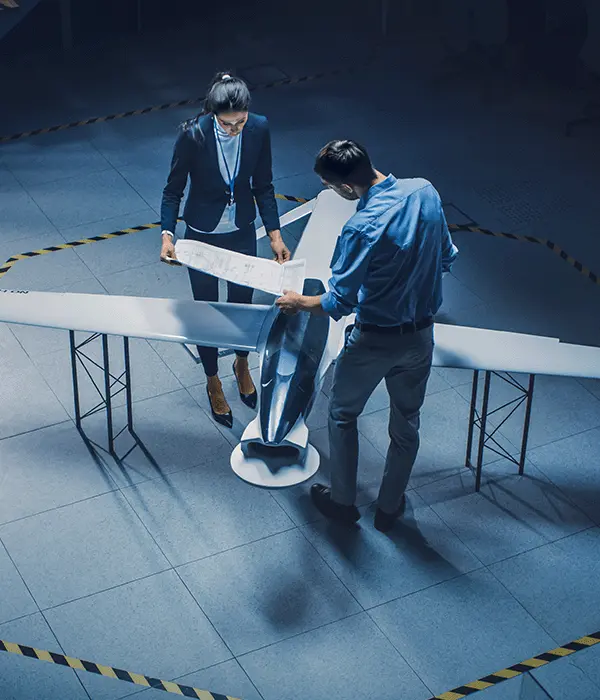 Team von Ingenieuren aus der Luft- und Raumfahrtindustrie arbeitet an einem unbemannten Luftfahrzeugkonzept. Konstrukteure arbeiten an pilotenloser Drohne. Industrieanlage mit Überwachungs- und Militärflugzeug. Erhöhte Aufnahme