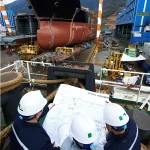Arbeiter sehen sich die Pläne der Werft an, Schiffbau