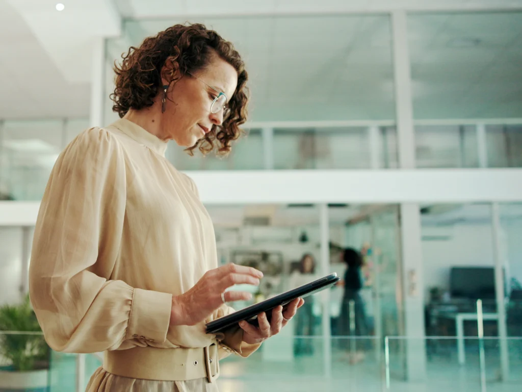 HR-Mitarbeiterin im Recruiting-Prozess prüft Bewerbungsunterlagen auf einem Tablet in einem modernen Büro.