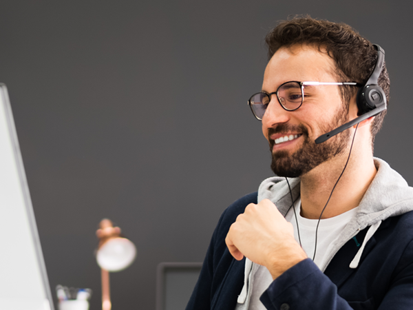 Mitarbeiter im Recruiting-Prozess führt ein Gespräch über ein Headset am Computer und koordiniert die Personal­anfrage eines Unternehmens.