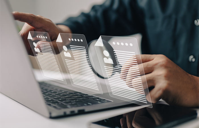 Person arbeitet am Laptop und durchsucht digital mehrere Bewerbungsunterlagen. Symbolbild für Karriereberatung und professionelle Unterstützung im Bewerbungsprozess.