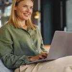 Frau arbeitet lächelnd an einem Laptop in einem modernen Büro – Beispiel für den erfolgreichen Einstieg über eine Direktvermittlung.