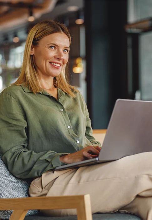 Frau arbeitet lächelnd an einem Laptop in einem modernen Büro – Beispiel für den erfolgreichen Einstieg über eine Direktvermittlung.