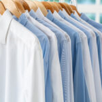 Ordentlich aufgereihte hellblaue und weiße Hemden in einem Schrank – klassische Kleidungsauswahl für den Business-Look beim Vorstellungsgespräch.