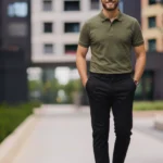 Mann in einem Business-Casual-Outfit für ein Vorstellungsgespräch, bestehend aus einem olivgrünen Poloshirt, schwarzer Stoffhose, schwarzen Lederschuhen und Armbanduhr. Das Outfit kombiniert Seriosität mit moderner Lässigkeit und ist ideal für Bewerbungsgespräche in Unternehmen mit gehobenem, aber nicht formellen Dresscode.