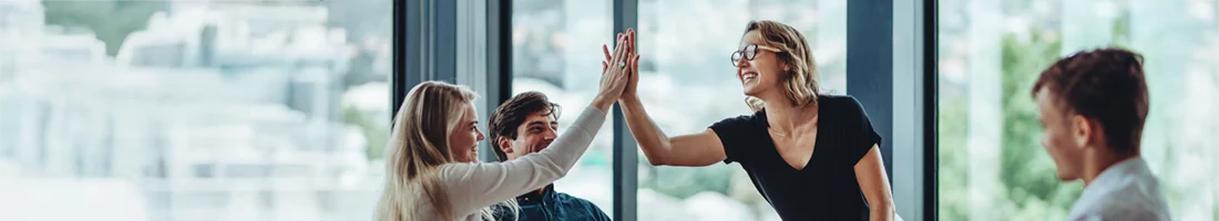 Teammitglieder geben sich in einem modernen Büro ein High-Five und freuen sich über erfolgreiche Zusammenarbeit in der Arbeitnehmerüberlassung.