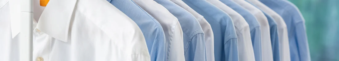 Ordentlich aufgereihte hellblaue und weiße Hemden in einem Schrank – klassische Kleidungsauswahl für den Business-Look beim Vorstellungsgespräch.