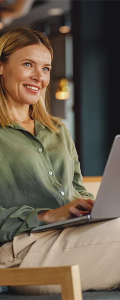 Frau arbeitet lächelnd an einem Laptop in einem modernen Büro – Beispiel für den erfolgreichen Einstieg über eine Direktvermittlung.