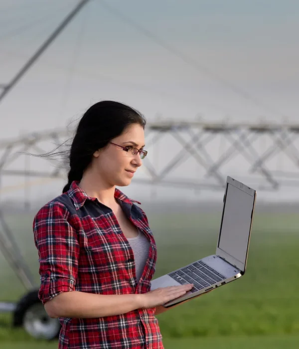 Frau mit Laptop auf bewässertem Feld